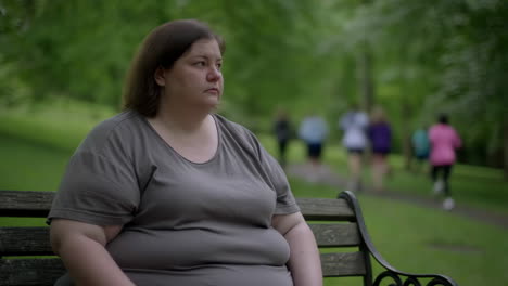 overweight woman sitting alone on a park bench