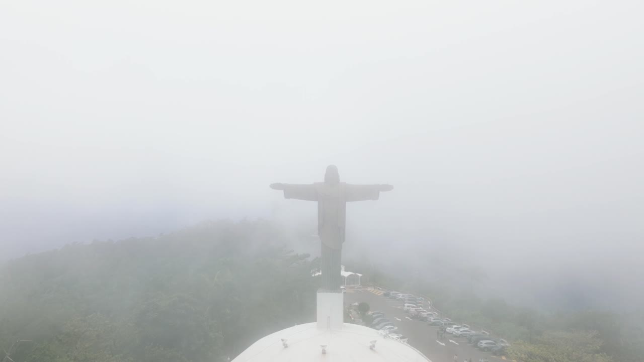 Misty view of Cristo Redentor statue in Puerto Plata, surrounded by fog in Dominican Republic, aerial pullback of Jesus Christ sculpture