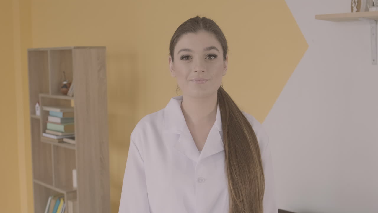 웃 고 카메라를 찾고 흰색 코트에 빨간 머리 의사 여자