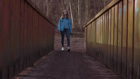 girl walks one a wooden bridge and stops in the middle