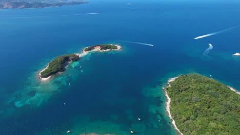 Islands-of-Ksamil:-A-Paradise-in-Deep-Blue-Seas-with-Corfu-on-the-Horizon,-Touring-Boat-Tracing-the-Waters-for-Summer-Vacation