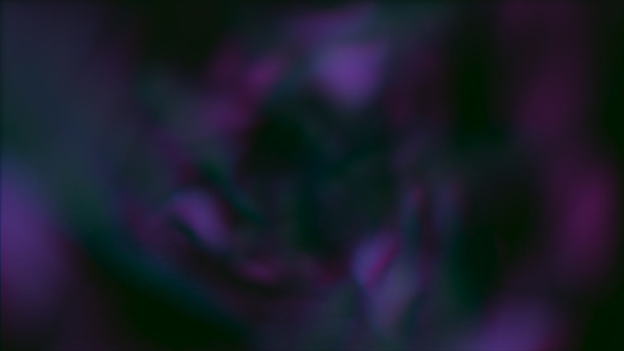 A vibrant, swirling vortex of purple, blue, and green hues spinning rapidly, creating a mesmerizing blur effect. The dynamic colors blend magnificently to form a captivating, swirling spectacle