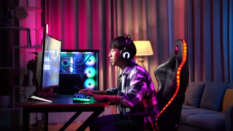 excited asian teen boy gamer playing video game on computer