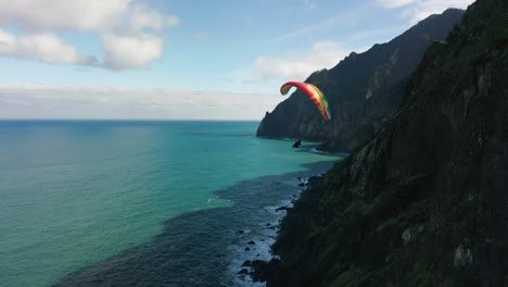 extreme paraglider flies close to shore of scenic madeira island, aerial