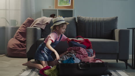 funny little girl puts and checks up garment heap in case