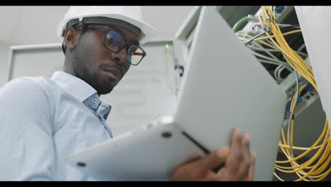 network technician working on laptop in server room