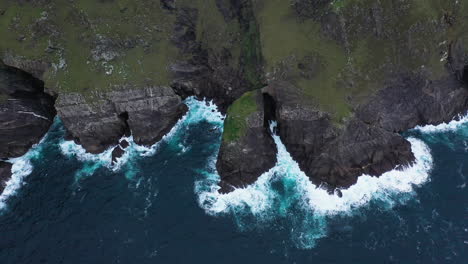 cinematic tilting upward drone shot of the ocean crashing against the edge near keem beach, ireland