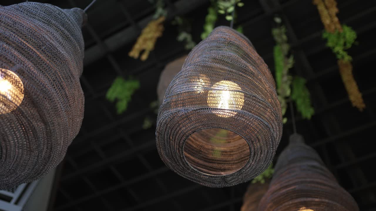 warm light glows through handcrafted woven shades with hanging greenery above