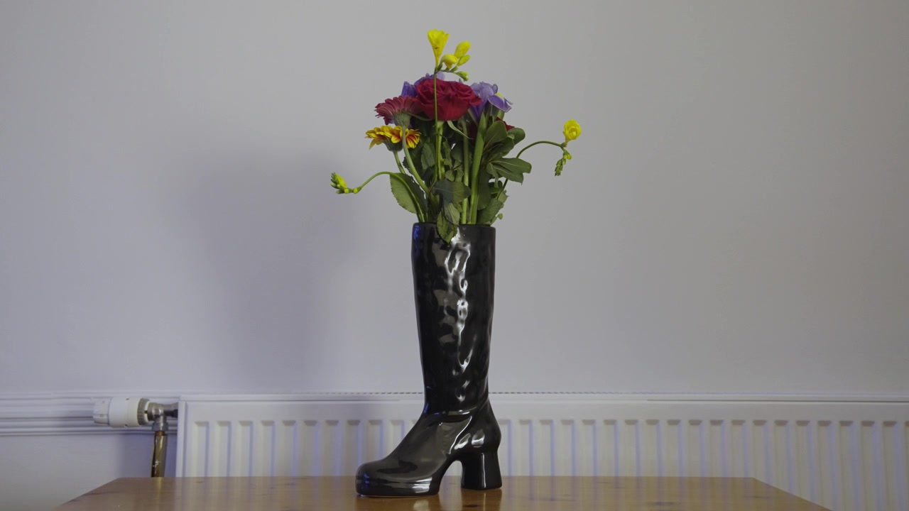Jarrón Estático con Forma de Bota con Flores, Pared Blanca y Mesa de Madera