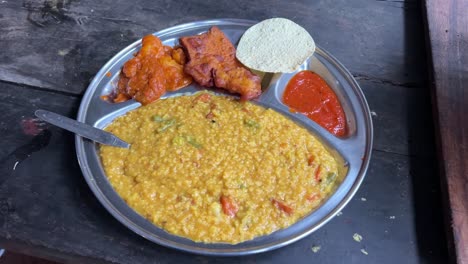 khichuri with alu dum, chutney and papad served on a plate by a bengali restaurant