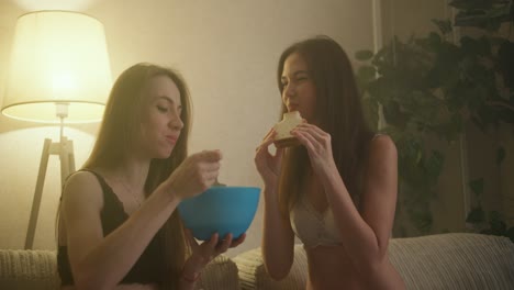 young woman lesbian couple are taking sandwiches and bowl, girl feeding her girlfriend