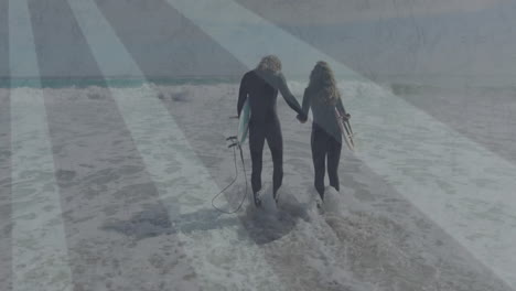 male surfer and female surfer walking into surf holding surfboards, displaying motion tech charts