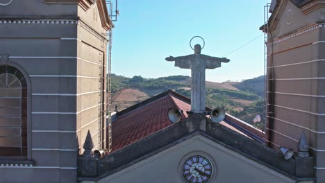 orbital aerial shot from top of church showing christ statue and blue sky and mountains in the background with sunlight streak