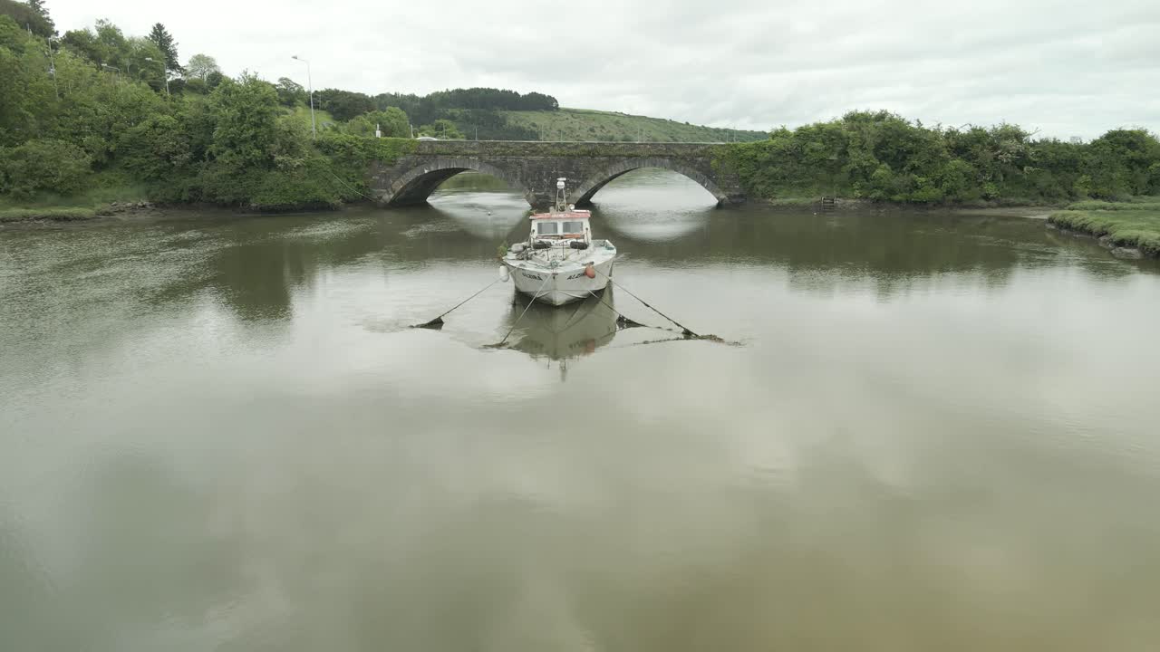 un viejo barco se encuentra abandonado en el río cerca de un puente de piedra en youghal, condado de cork, irlanda