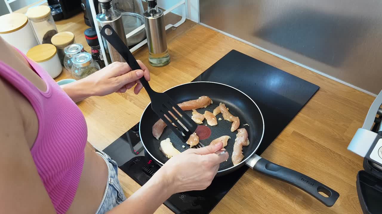mujer cocinando pollo en la cocina