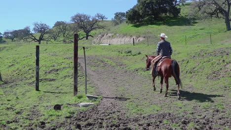 Cowboy-leaves-his-set-of-corrals-riding-up-the-road