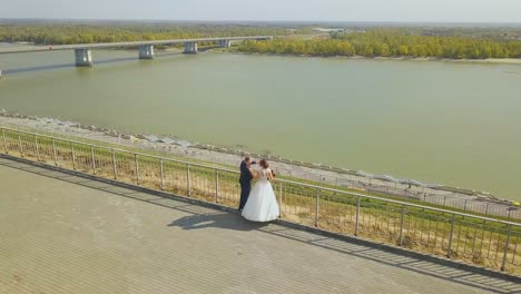 just married couple at handrail on hill at river aerial view