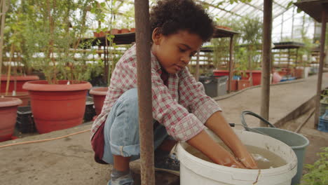 african american boy washing hands in greenhouse