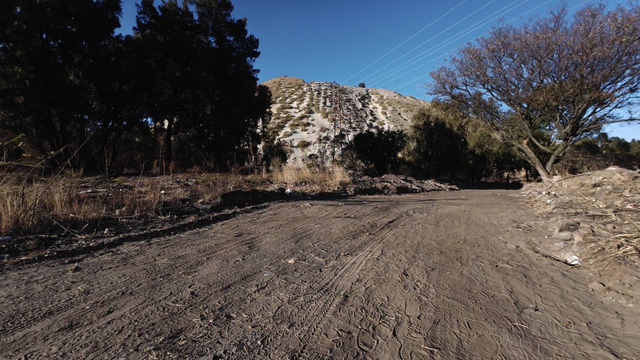 gravel road with mine dump in the background surrounded by trees