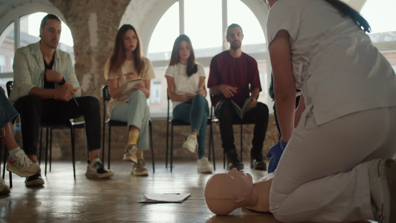 뒷면:  유니폼을 입은 여성 의사가 대중을 위해 의료 인형에서 실용적인 의료 훈련을 수행합니다.