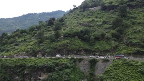 a drone shot of commercial vehicles traveling on a suspended bridge on a river valley in the remote highway of himachal pradesh, at the foothills of the indian himalayas