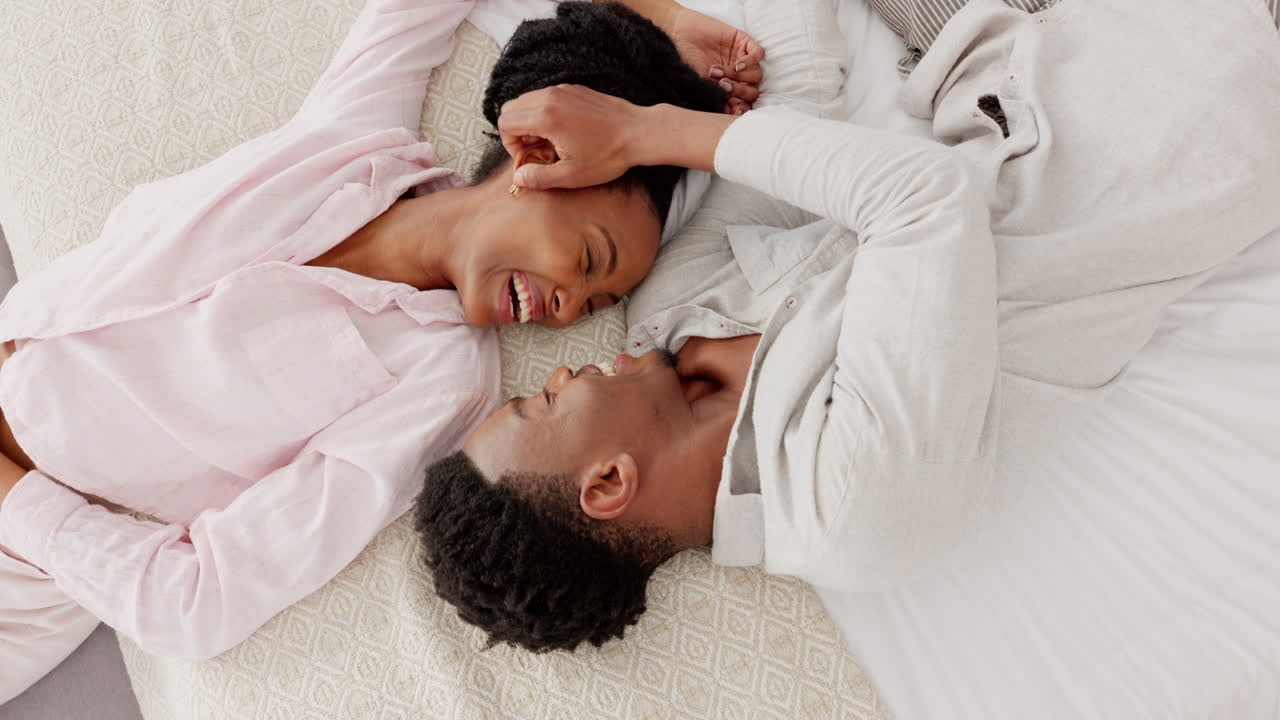 Love, black couple and kiss top view on their bed