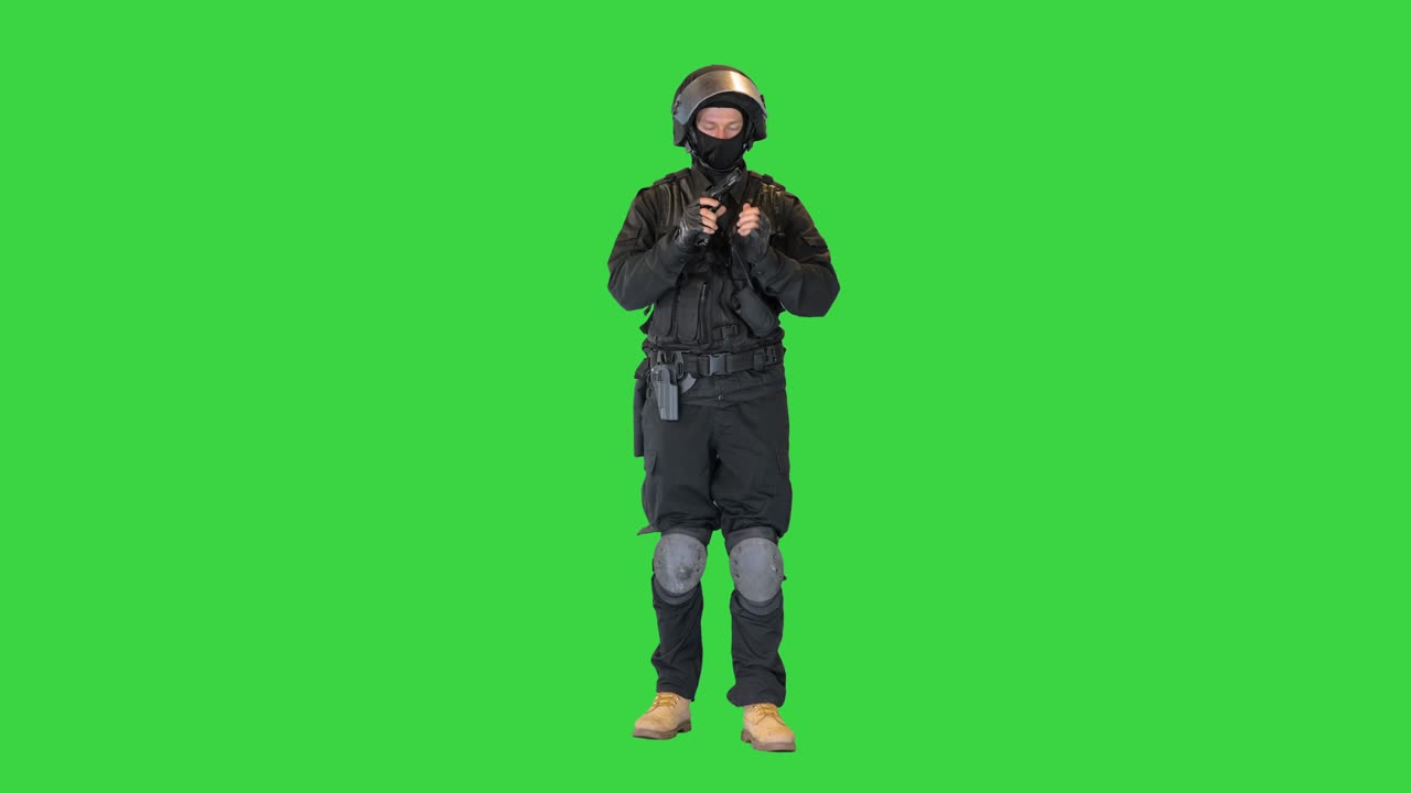 Police tactical officer checking his hand gun and folding hands on a Green Screen, Chroma Key