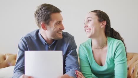 A-young-caucasian-couple-talking-and-paying-their-bills-using-a-laptop