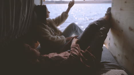 two girls are lying in the back of a caravan by a lake 1