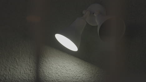 dos conos de luz led de color blanco están instalados en la pared gris, de los cuales solo uno está encendido