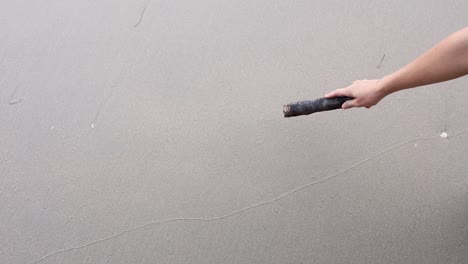 hand etching a heart shape on a sandy surface.