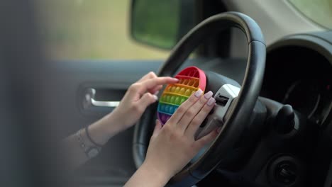 woman using pop it or simple dimple in car.