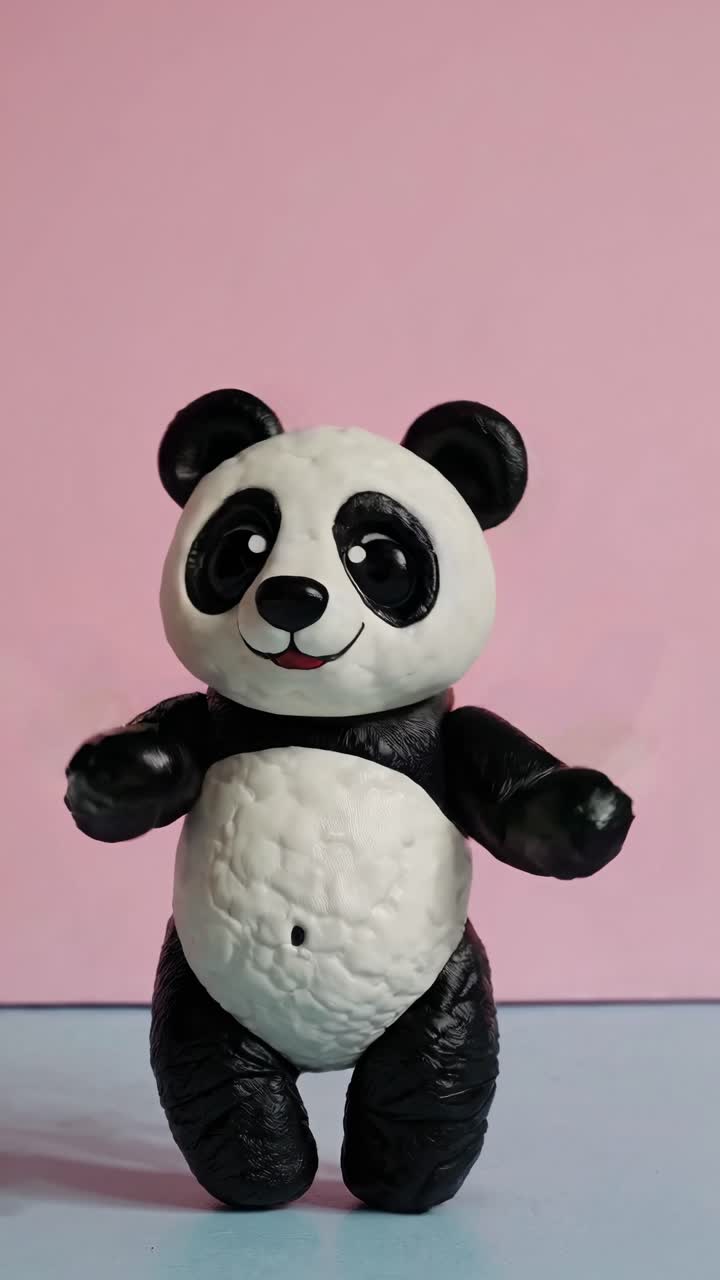 Un'allegra statuetta di panda in argilla viene immortalata a mezz'aria su uno sfondo rosa pastello