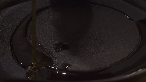 cooking oil falling on bottom of black frying pan