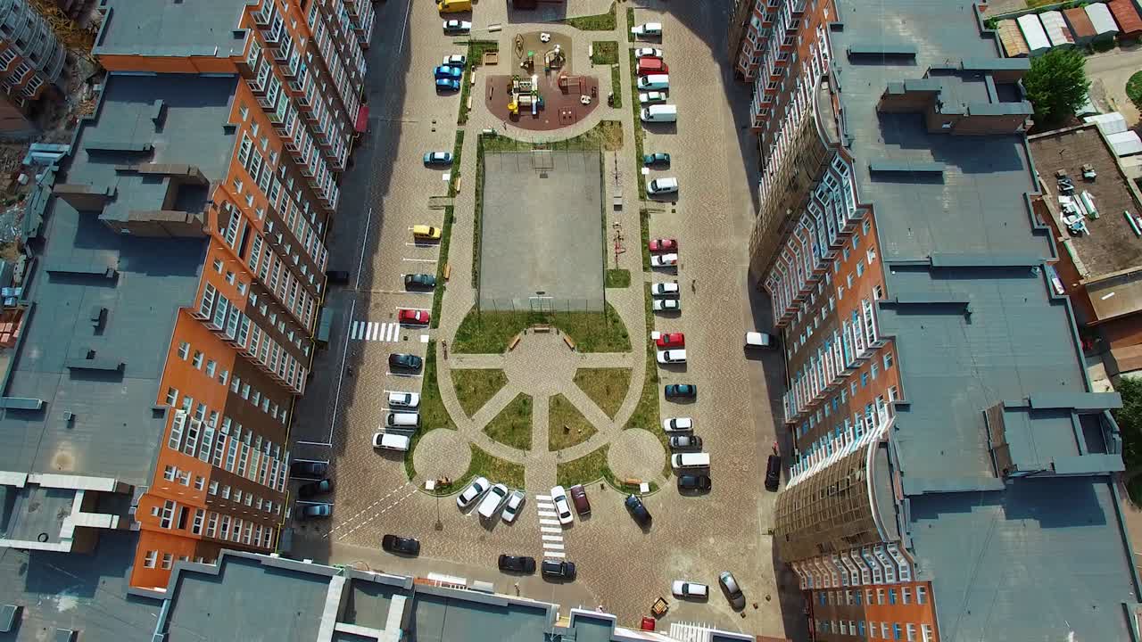 Top down view of infrastructure of a modern residential area. Modern place with parked cars between high-raised buildings. Drone video footage.