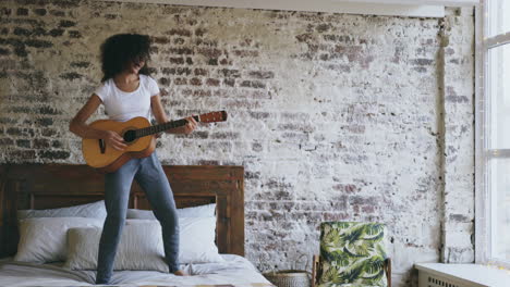 woman playing acoustic guitar on bed