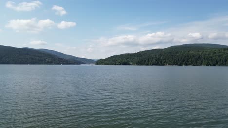 Landscape-of-majestic-Zywiec-lake-in-Beskid-mountains-under-a-blue-sky---aerial-view-4K