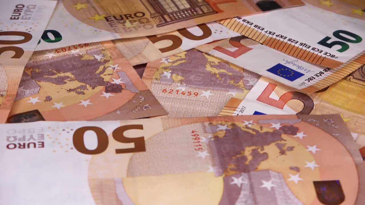 un primer plano en bucle de numerosos billetes de euro colocados uno encima del otro en una placa giratoria.