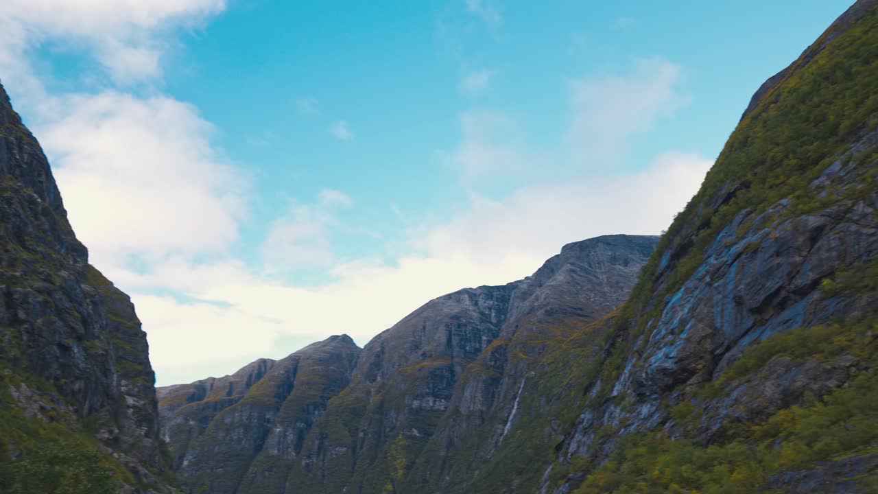 푸른 하늘과 흰 구름을 배경으로 높은 산의 아름다운 경치를 카메라 패닝 및 공개