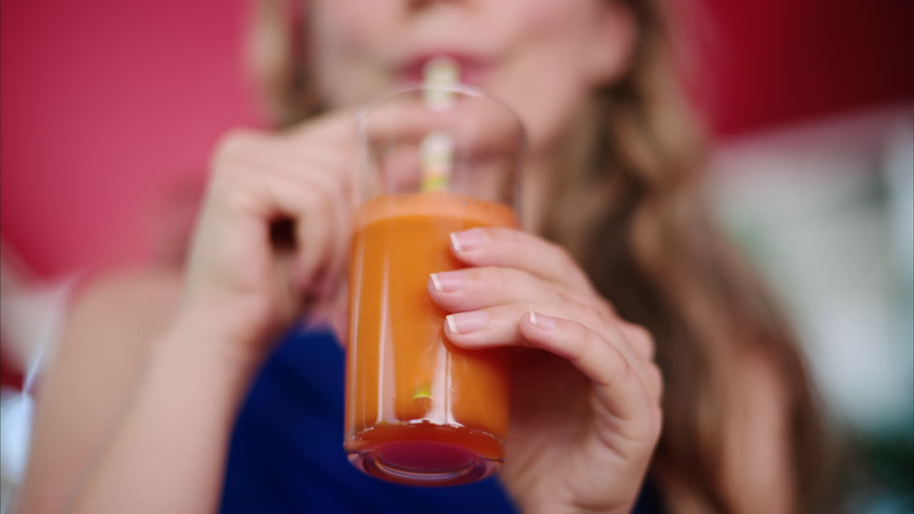 Woman in a blue dress drinking a carrot juice at a restaurant terrace