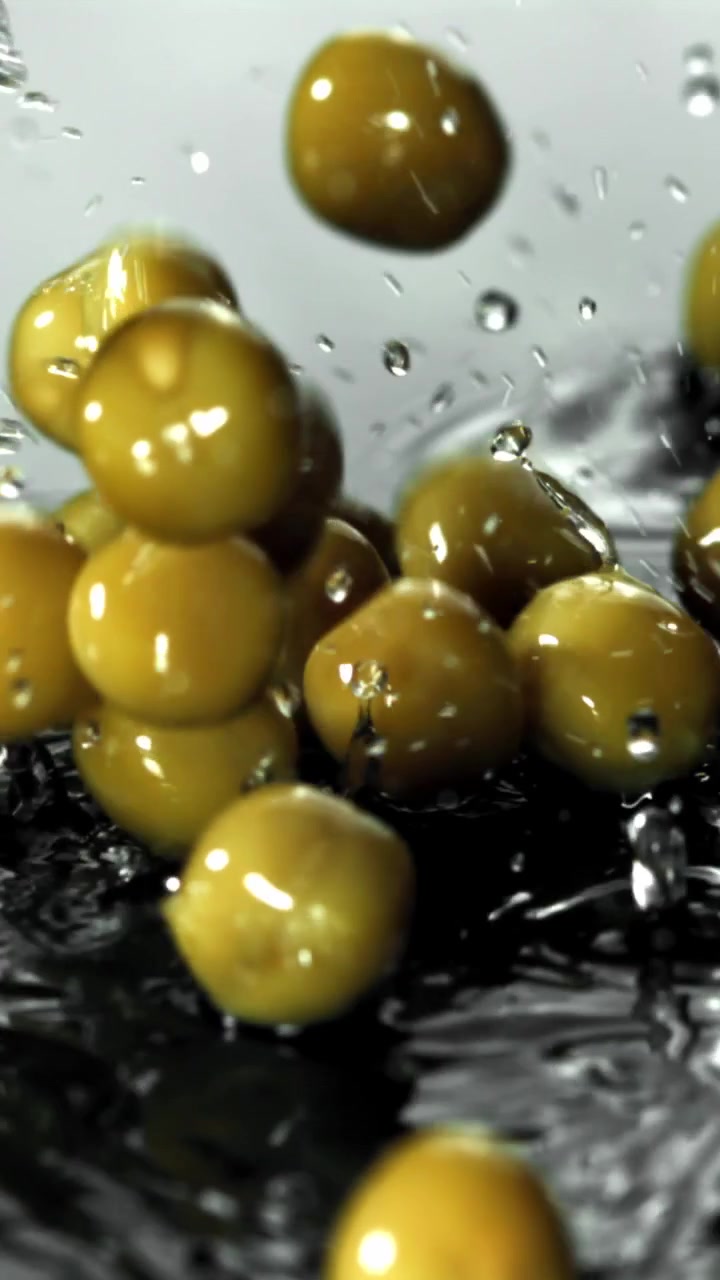 Movimento rallentato di olive verdi che cadono e schizzano nell'acqua