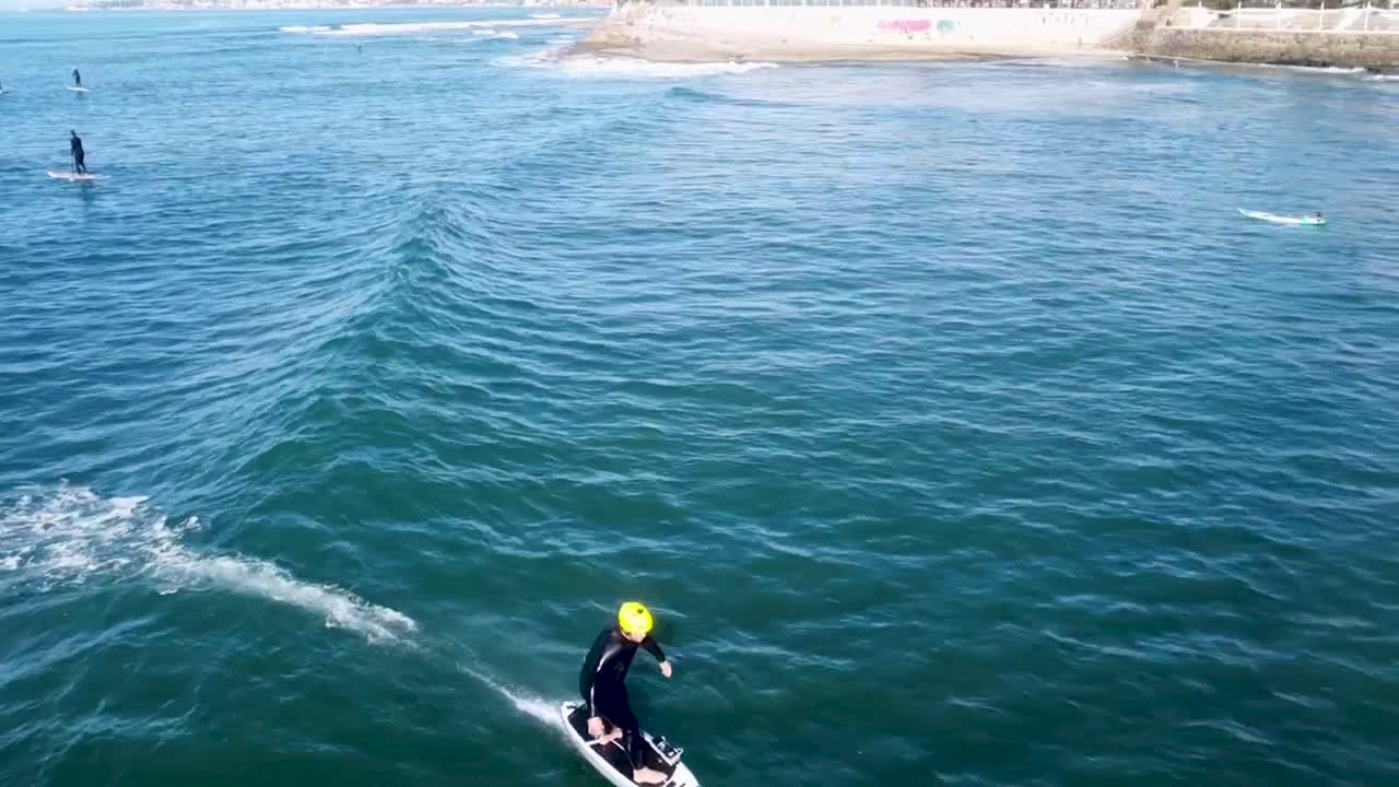 vista aérea hacia atrás de un surfista curvando con su jetsurf. españa