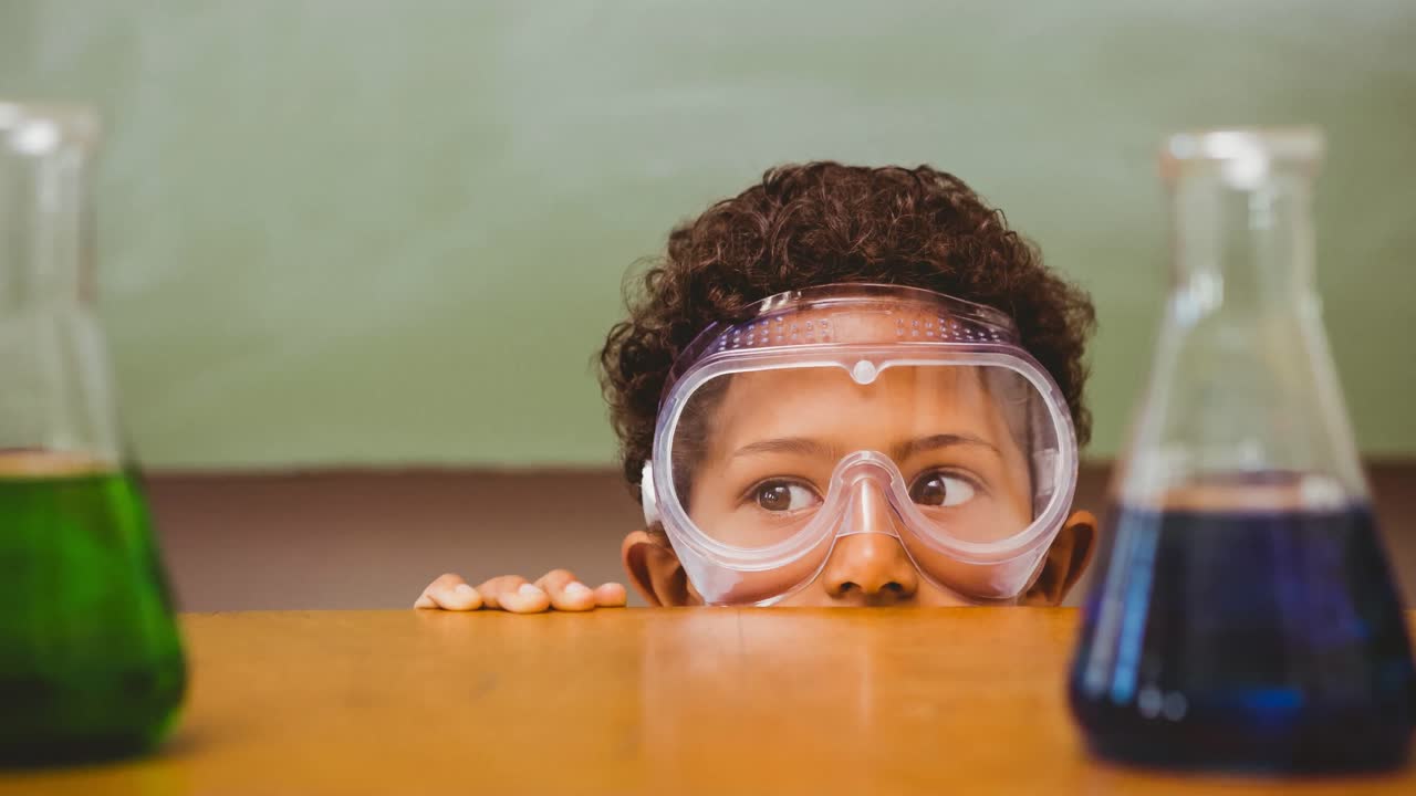 niño de escuela con gafas de protección en el laboratorio en la escuela