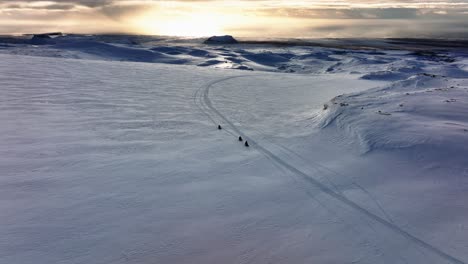 aerial view of people riding snowmobiles on myrdalsjokull glacier in iceland, during an epic sunset