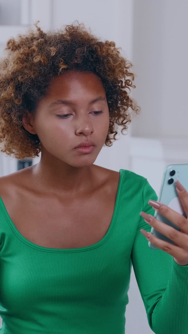 Woman interacting with smartphone wearing green top in bright interior setting