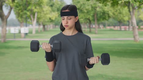 serious indian girl lifting heavy dumbbells