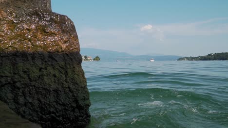 lake water waves splashing on stone close up, view from shore, lakeside panorama