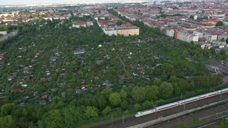 Luftaufnahme-Des-Schnellzugs,-Der-Entlang-Eines-Blocks-Von-Gemeinschaftsgärten-In-Der-Stadt-Fährt.-Ruhiges-Wohnviertel.-Berlin,-Deutschland