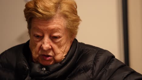 old woman wearing a coat at home talking with someone. portrait