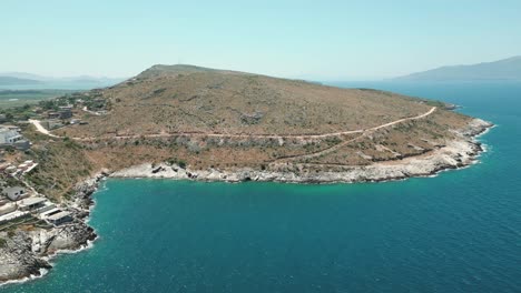 Albanien,-Malerischer-Berg-Mit-Einer-Straße-Am-Blauen-Wasser-Des-Ionischen-Meeres